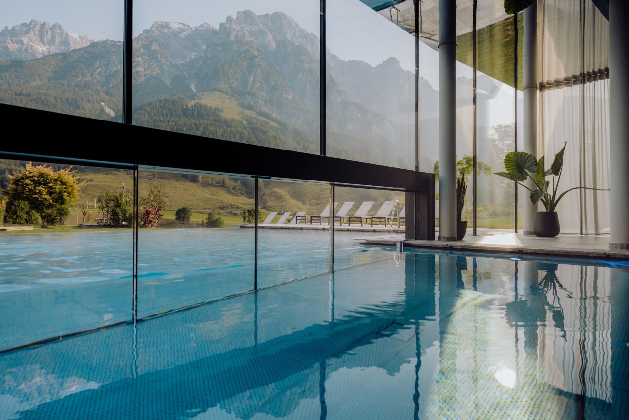 Indoorpool mit großer Glasfassade und Blick auf Berge