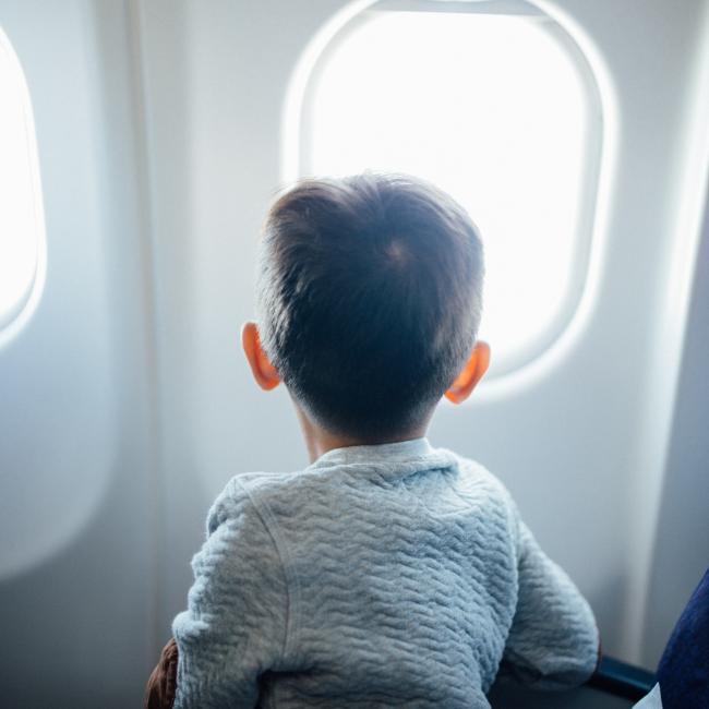 Kleines Kind, das aus einem Flugzeugfenster schaut