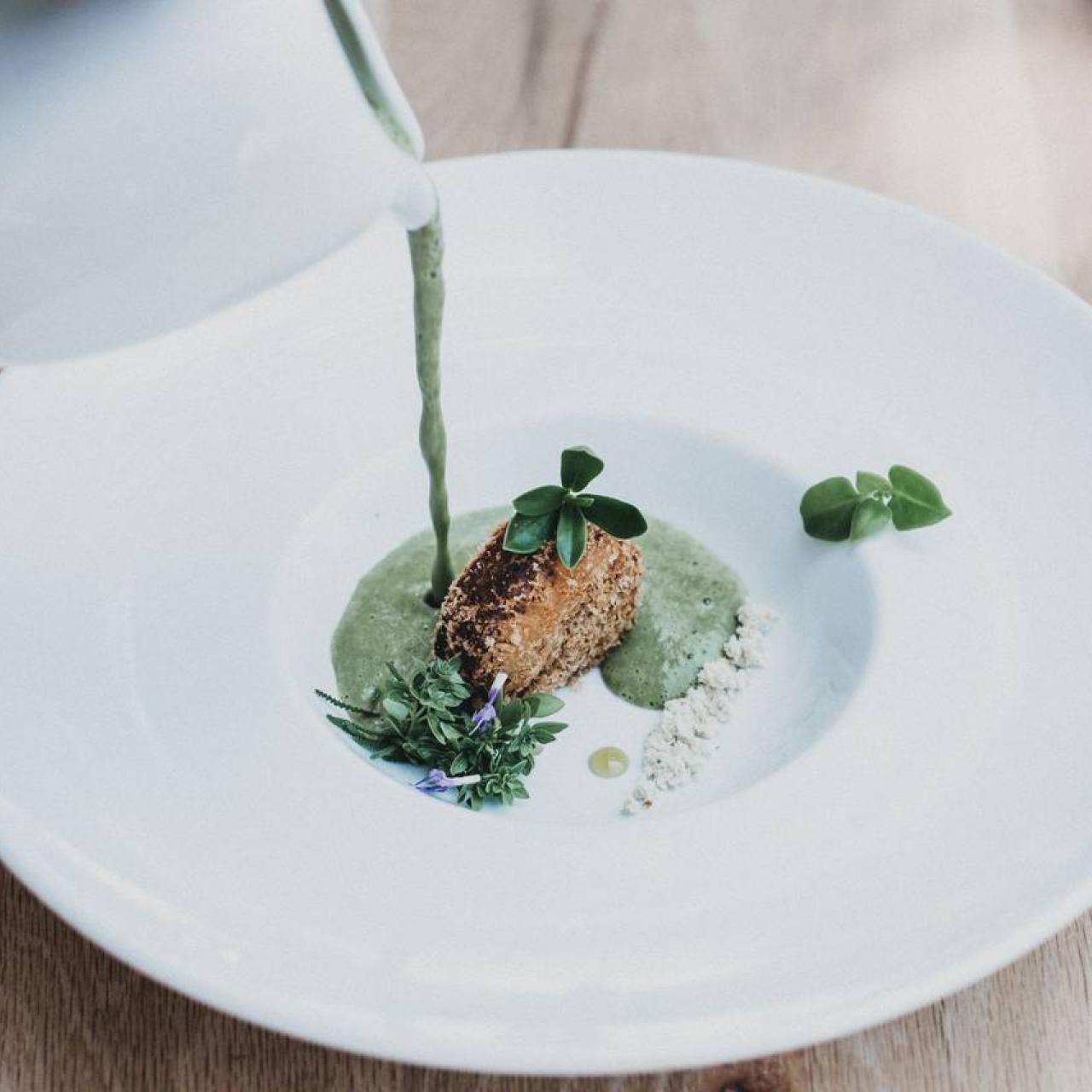 Gericht mit grüner Soße auf einem weißen Teller