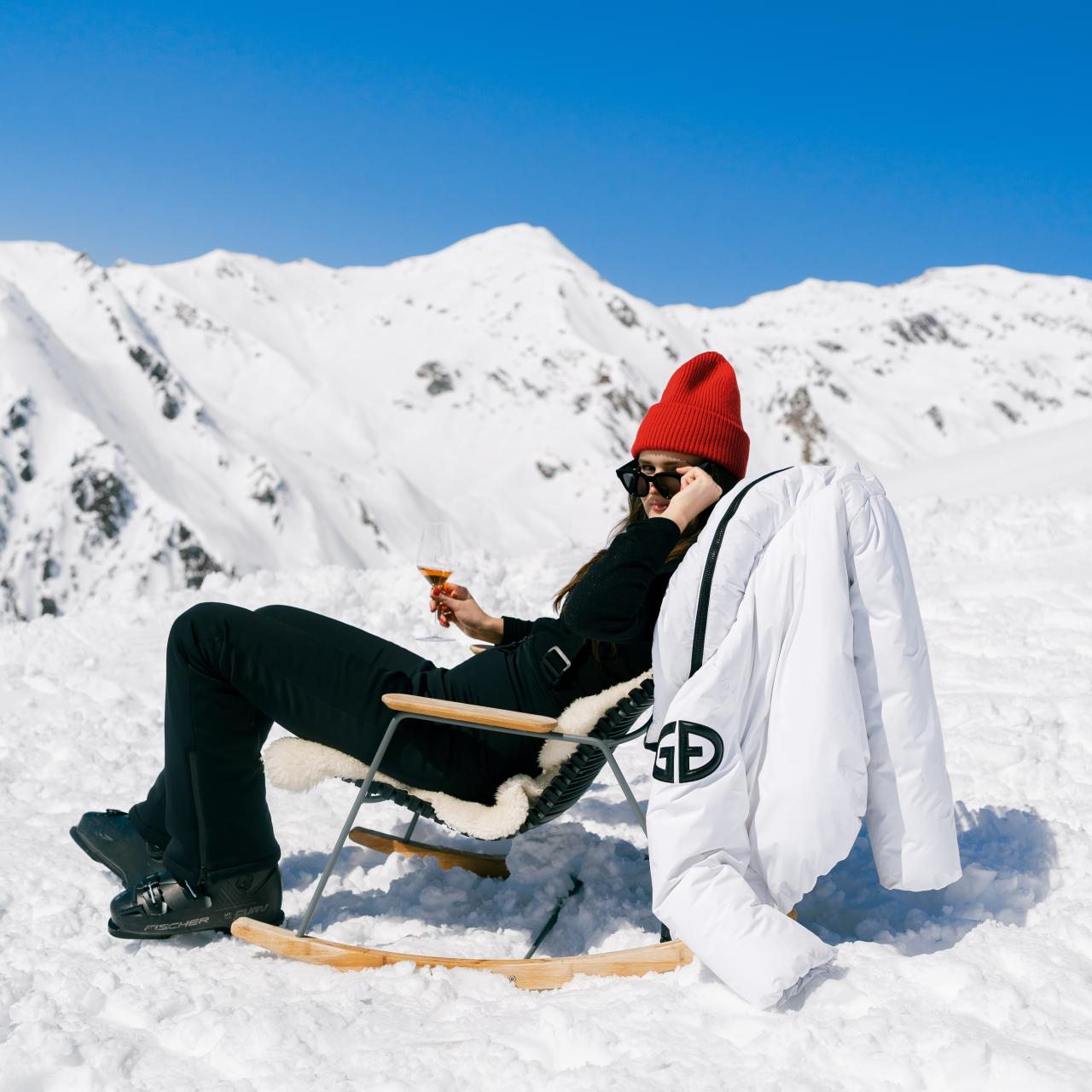 Frau mit Sekt im Liegestuhl beim Skiurlaub