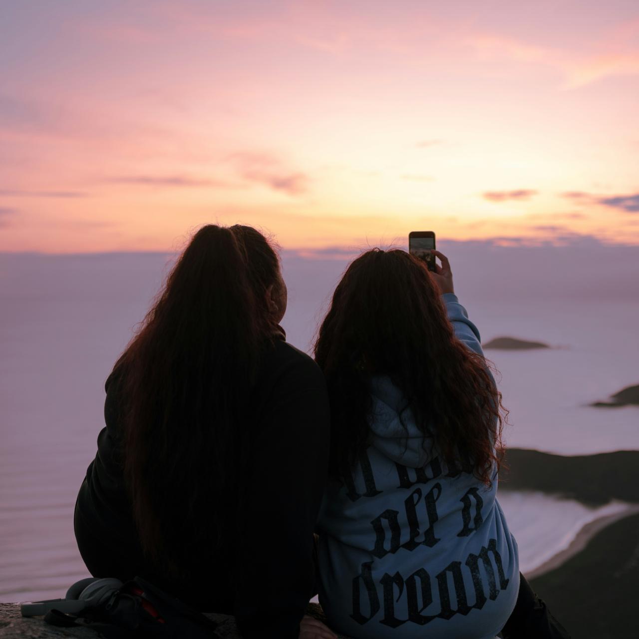 Freundinnen filmen Sonnenuntergang mit Handy