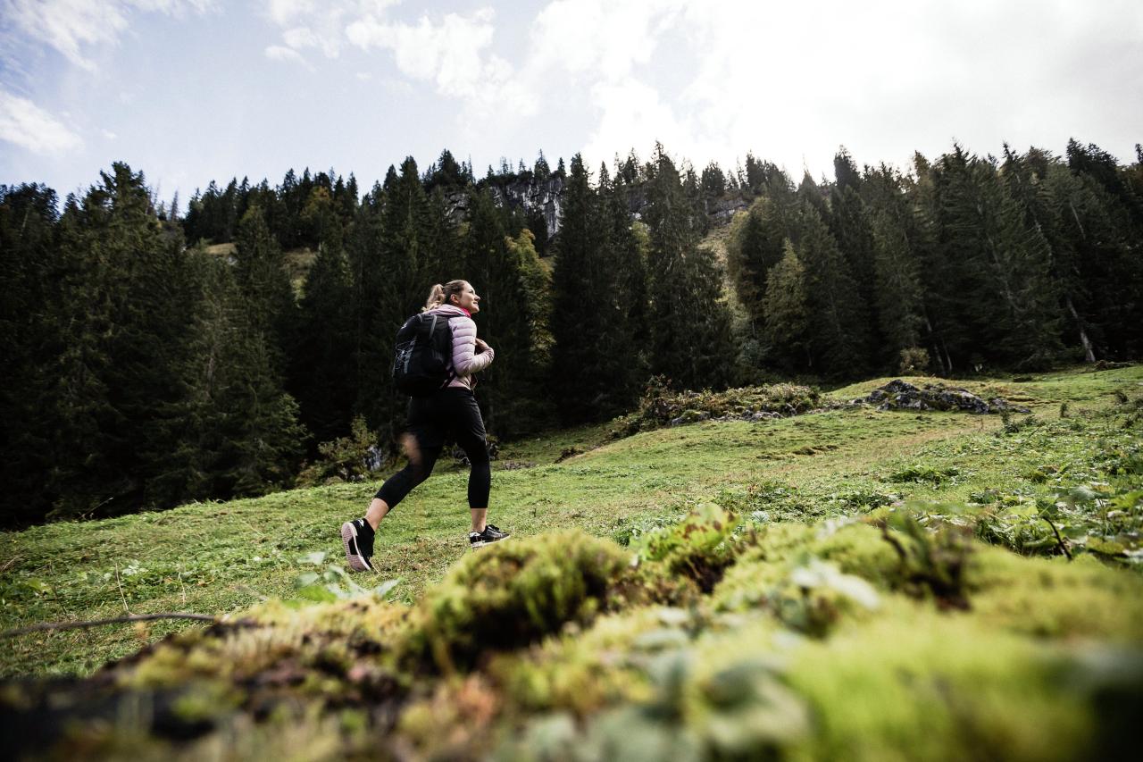 Eine Frau mit Rucksack, die über eine grüne Wiese läuft