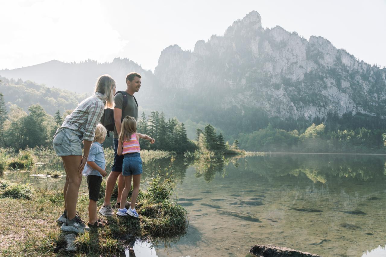 Eine Familie mit zwei Kindern am Ufer eines Bergsees