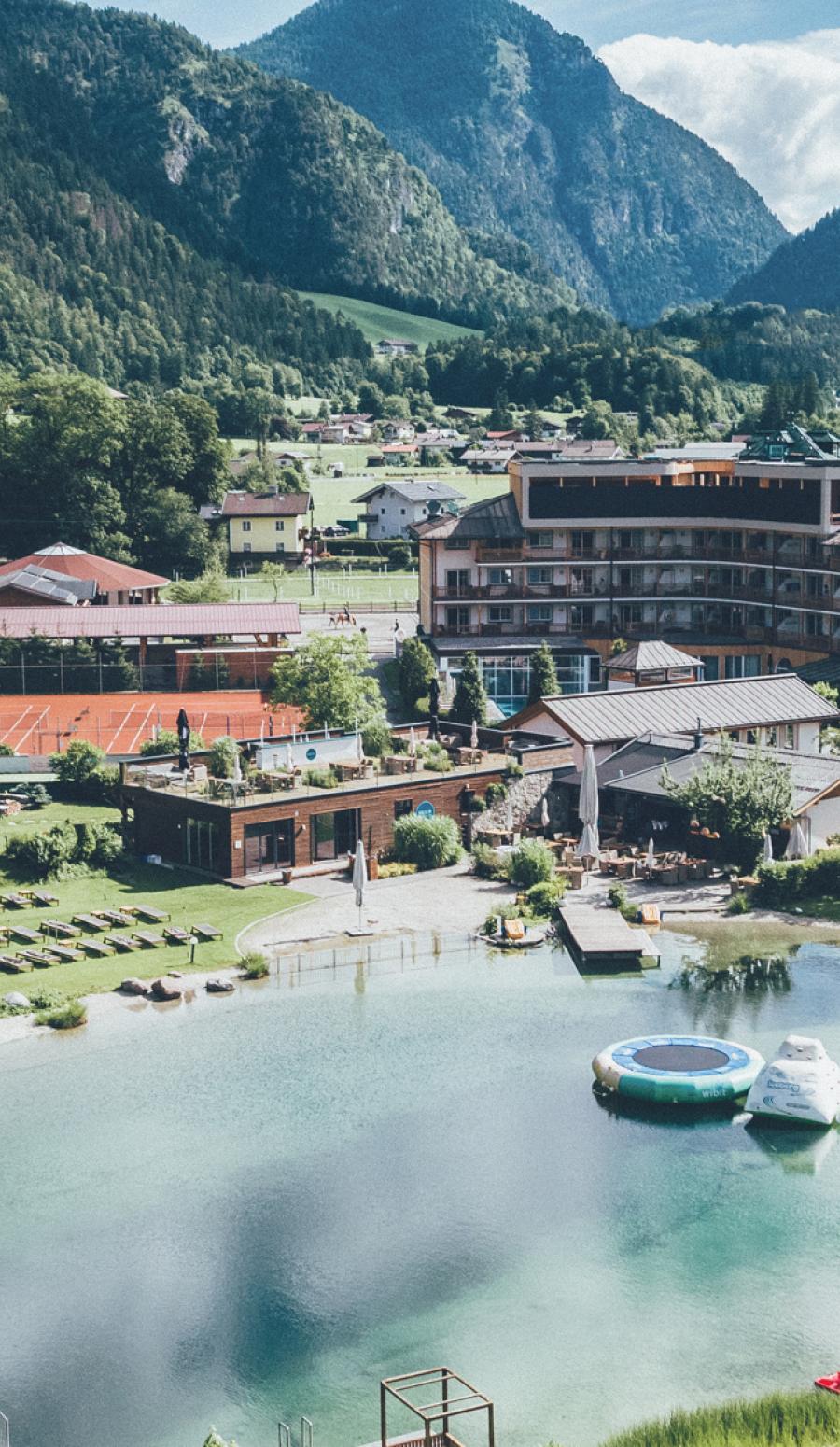 Großer Badeteich mit Hotel am Ufer und Berge im Hintergrund
