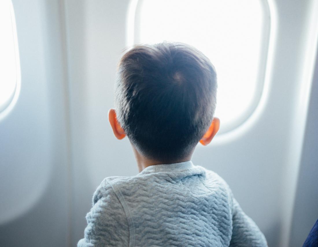 Kleines Kind, das aus einem Flugzeugfenster schaut