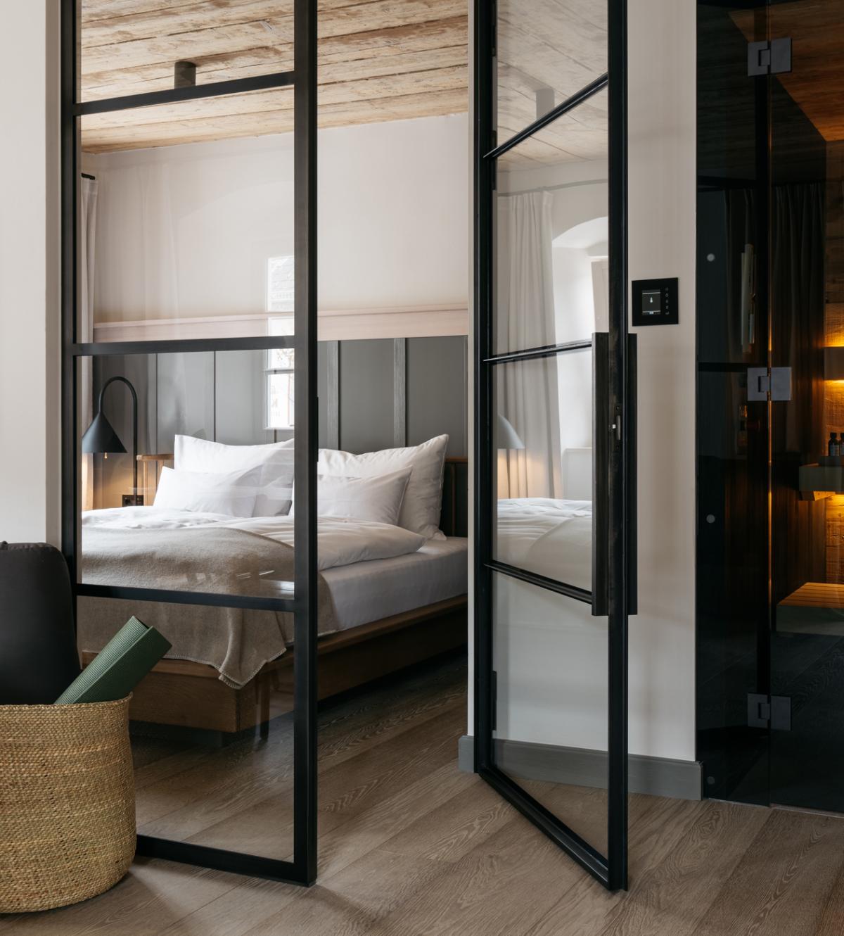Hotelzimmer mit kleiner Sauna, Fernsehen und einem Bett hinter einer Glastür
