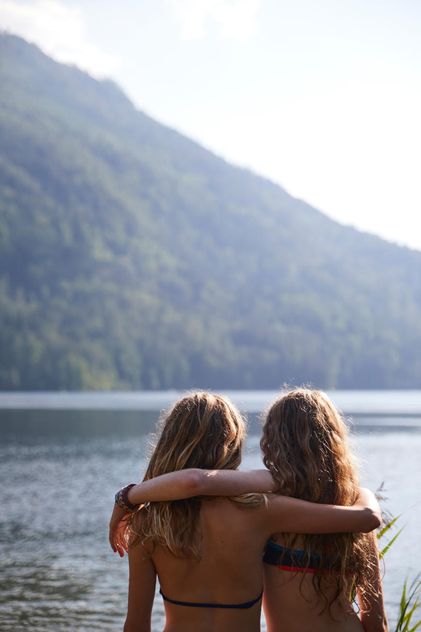Zwei Frauen, die am Arm in Arm am Seeufer stehen