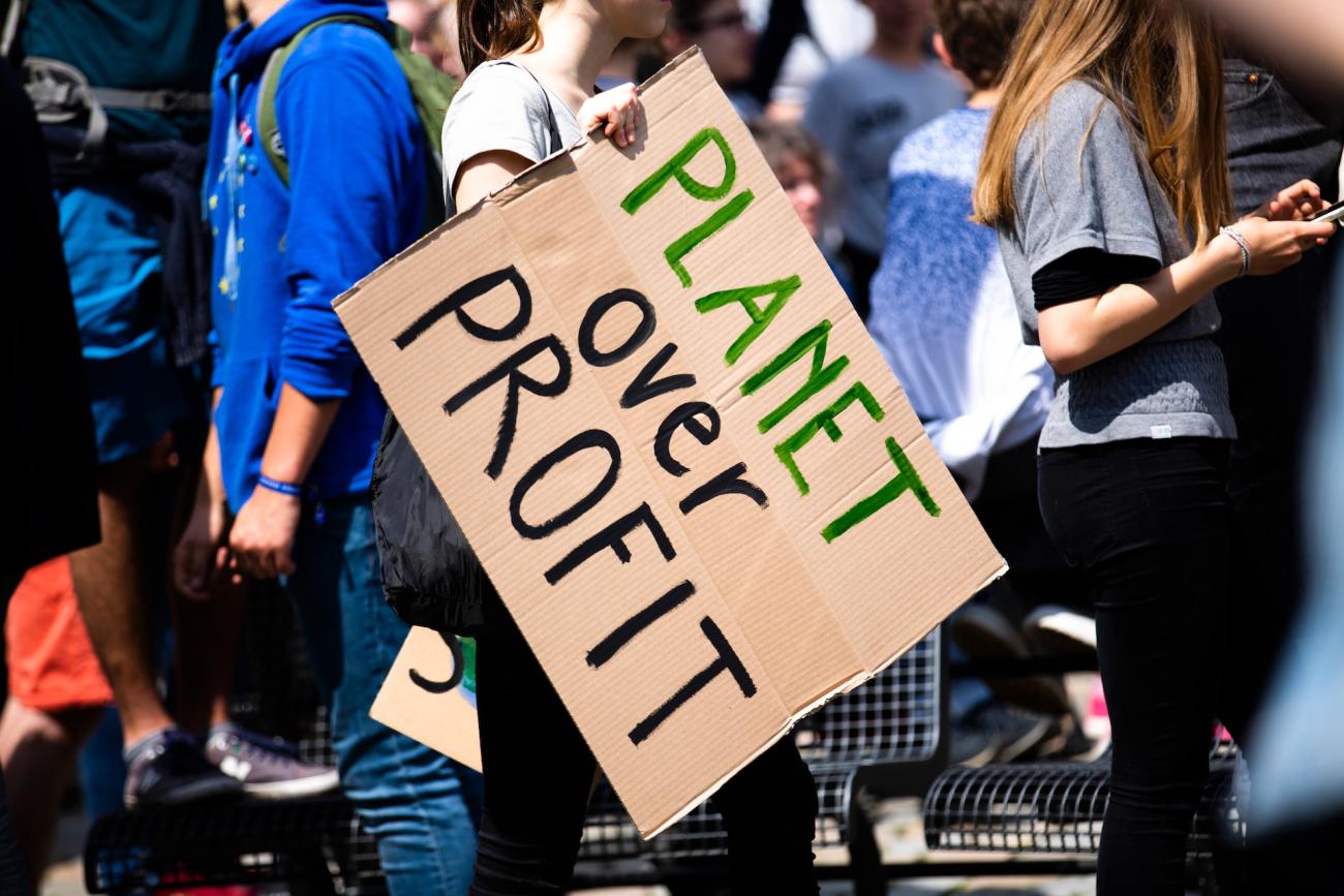 Pappschild auf einer Demo mit dem Text Planet over Profit