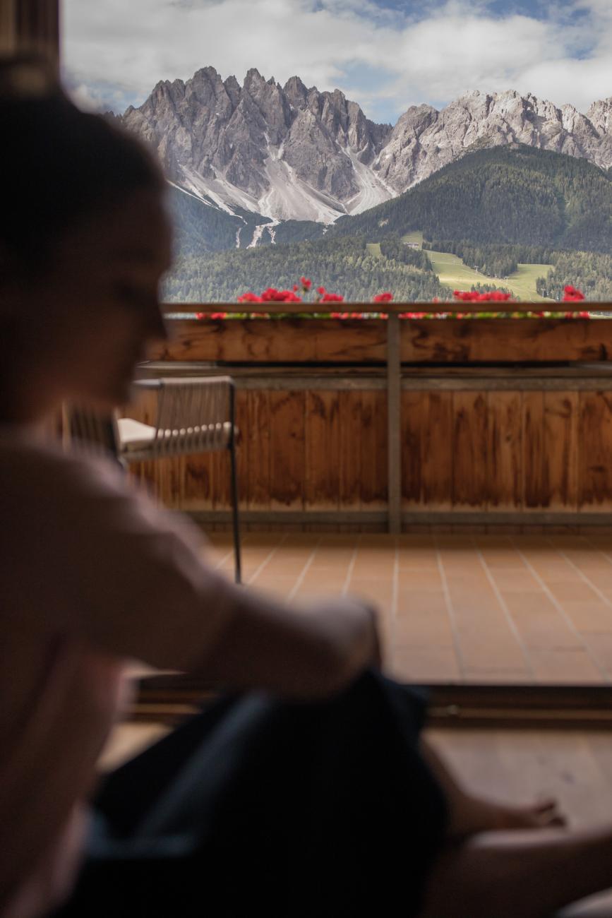 Frau sitzt auf einer Terrasse mit Blick auf die Dolomiten