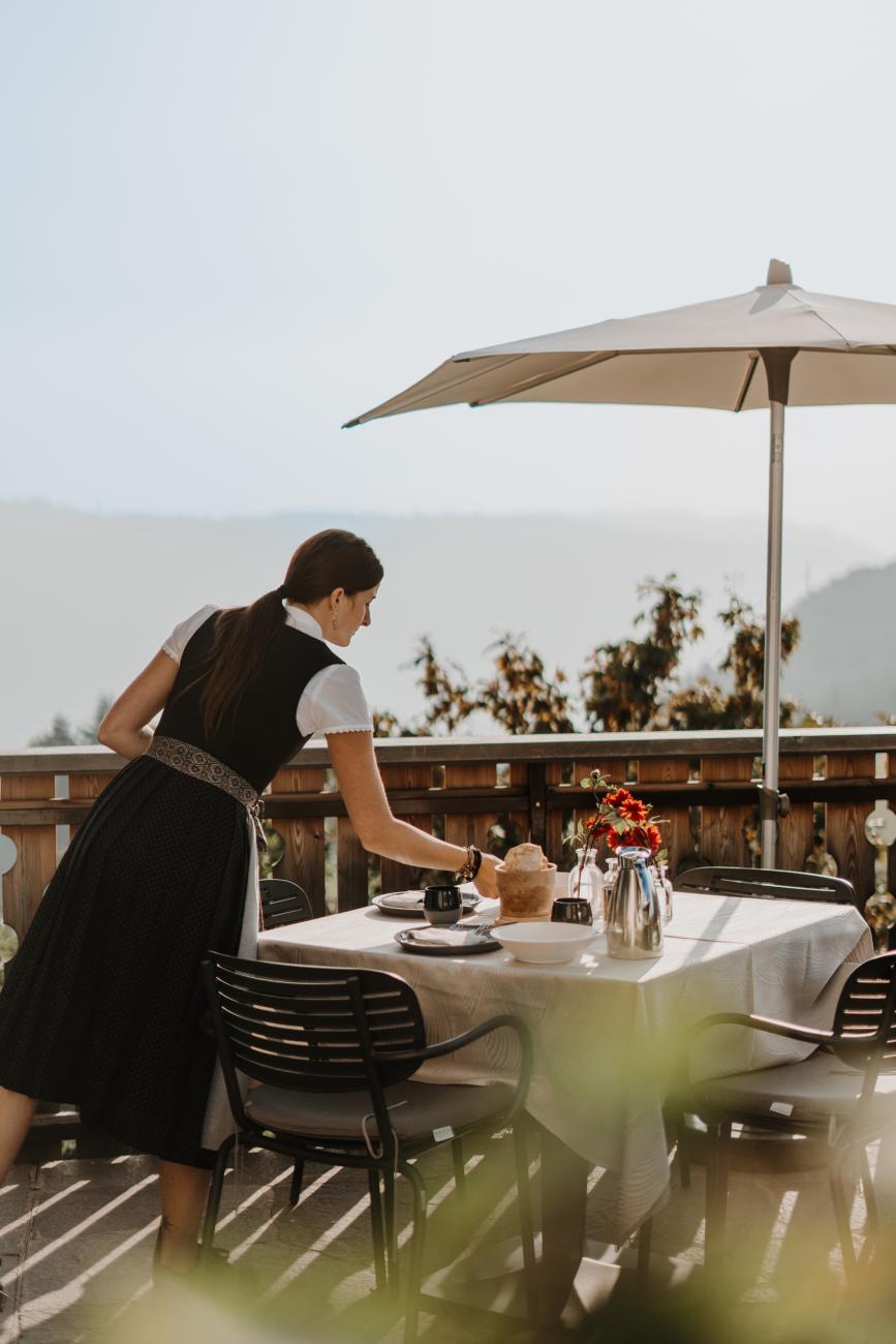 Frau, die einen Tisch auf einer Terrasse deckt