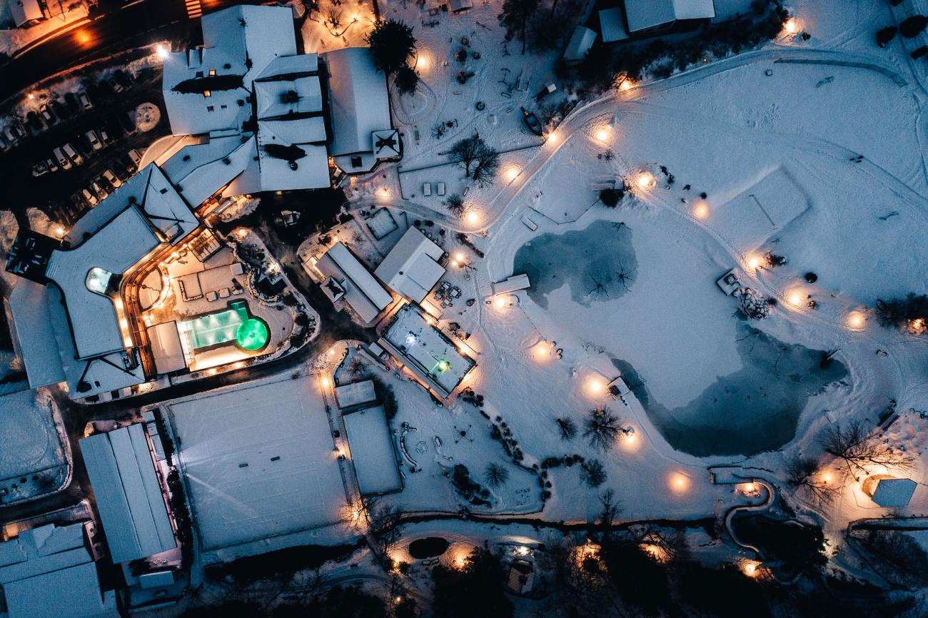 Drohnenansicht von einem verschneiten Hotel bei Nacht von oben