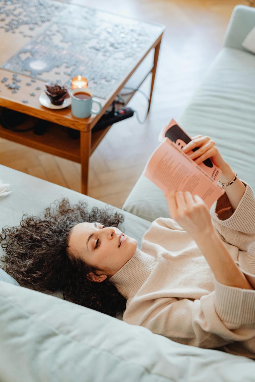 Frau liegt auf der Couch und liest ein Buch