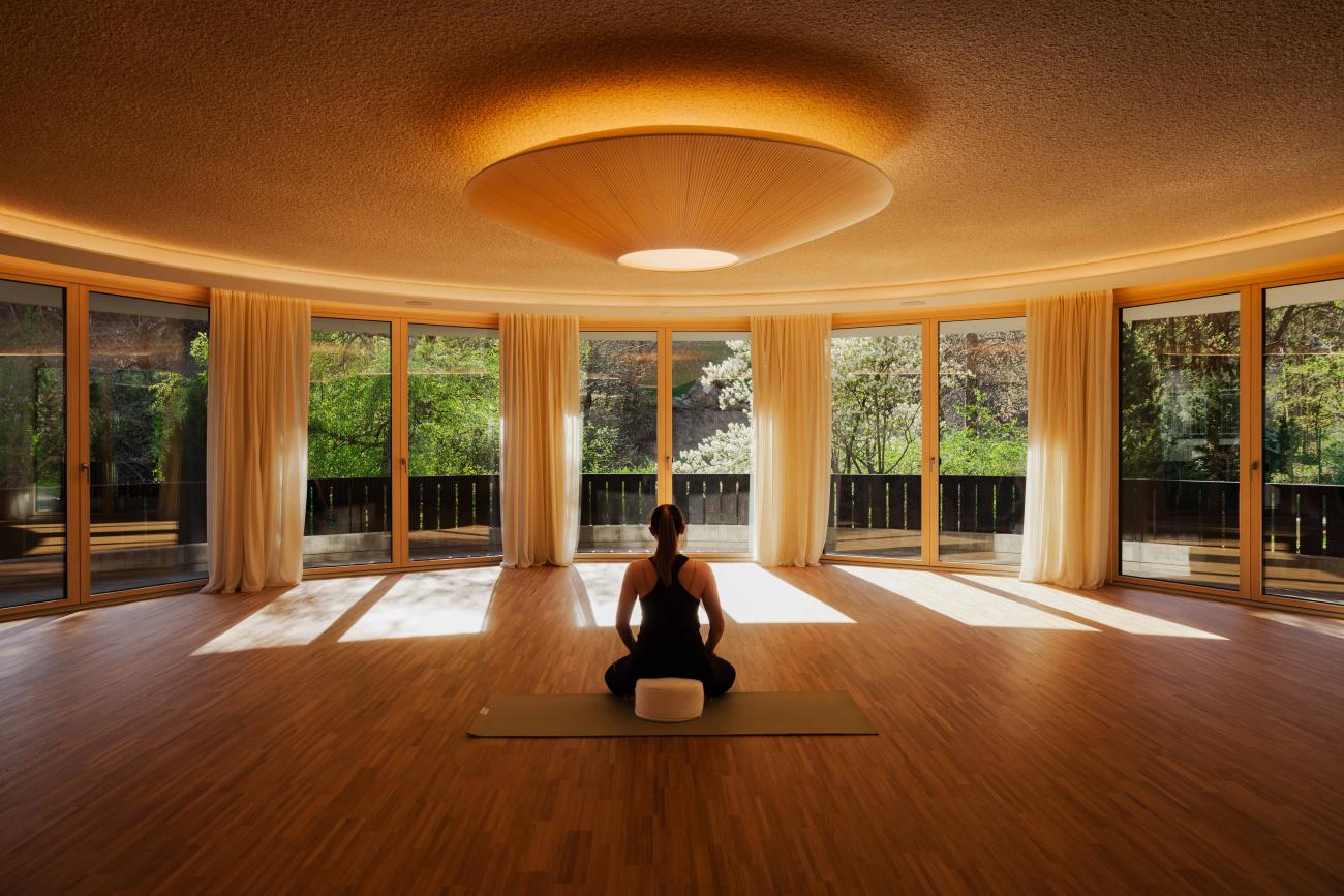 CMH_Waldhof2_Yogahaus_innen mit Frau die auf einer Matte sitzt