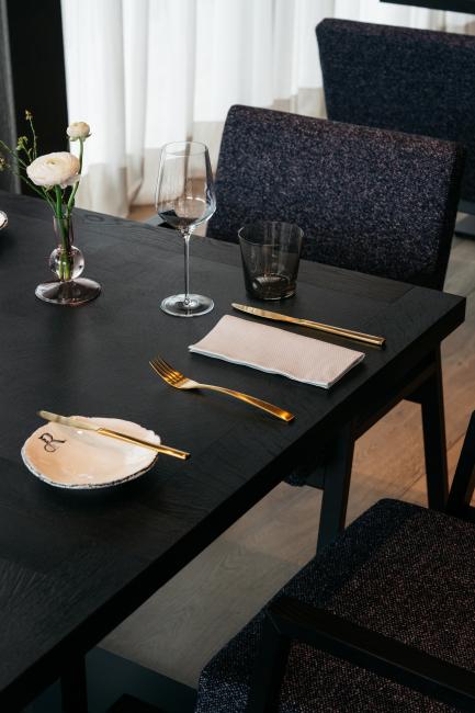 Schwarzer Tisch auf dem ein leeres Weinglas und Besteck liegt