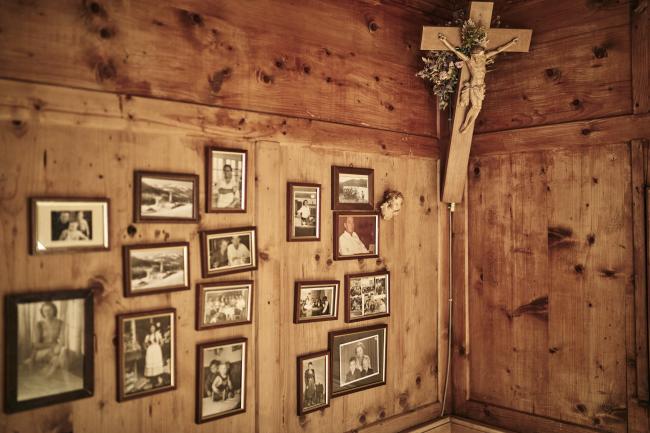 Eine Holzwand mit Kreuz und mehreren gerahmten Fotos