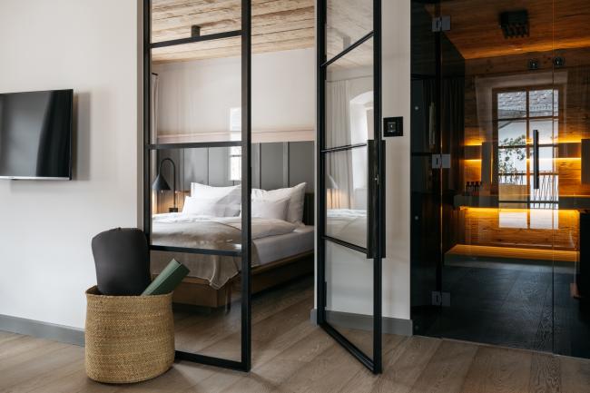 Hotelzimmer mit kleiner Sauna, Fernsehen und einem Bett hinter einer Glastür