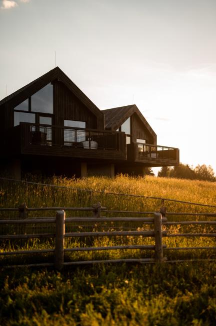 Holzhaus mit großer Glasfassade auf einem Hügel in der Abendsonne