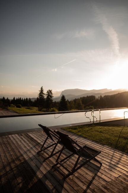 Länglicher Infinity Pool mit Holzsteg im Sonnenuntergang