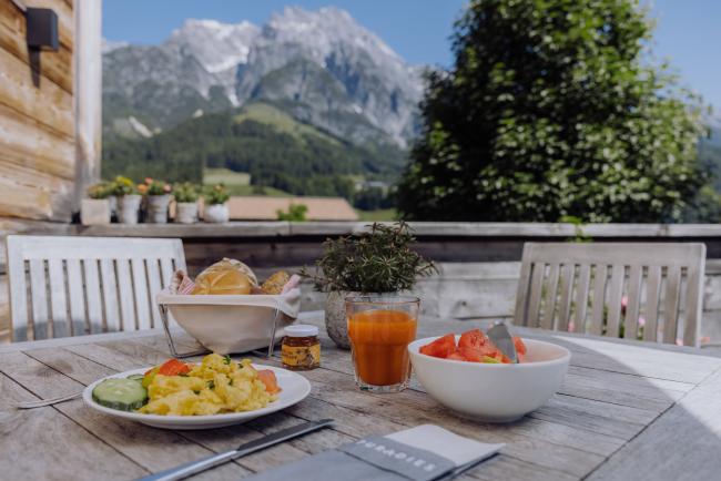 Essen auf einem Holztische mit Bergen im Hintergrund