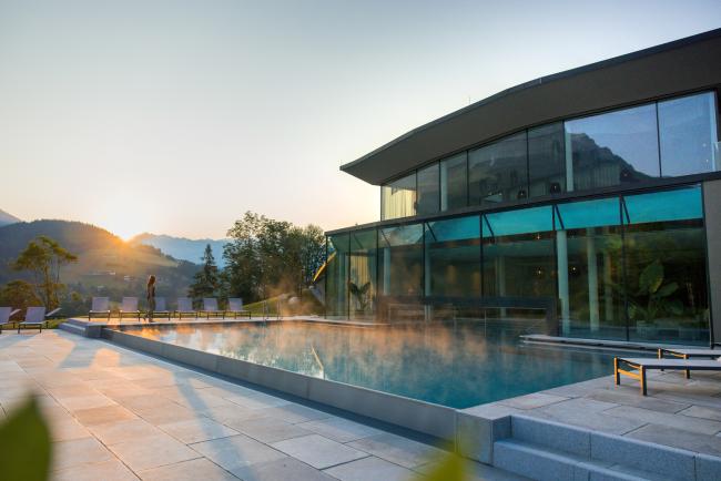 Haus mit Glasfassade und Pool im Sonnenuntergang