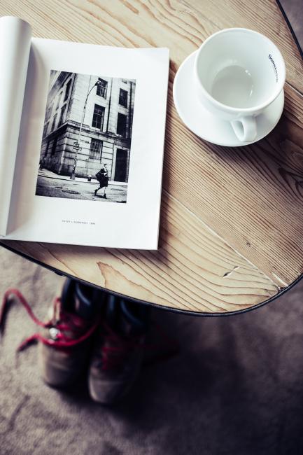 Holztisch, auf dem ein Magazin und eine weiße Kaffeetasse steht