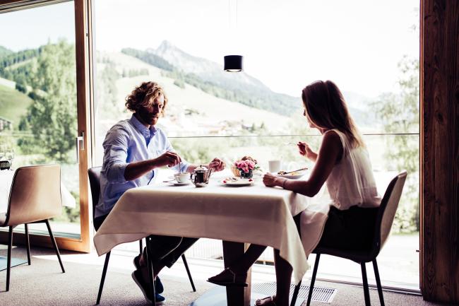 Frau und Mann, die an einem Tisch vor einer Terrasse sitzen und essen