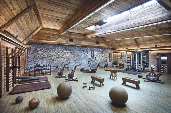Fitnessraum mit verschiedenen Geräten und Holzwände