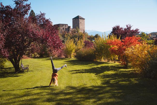 Frau, die auf einer großen herbstlichen Wiese ein Rad schlägt