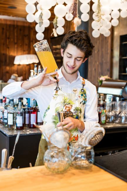 Barkeeper, der einen orangen Drink zubereitet