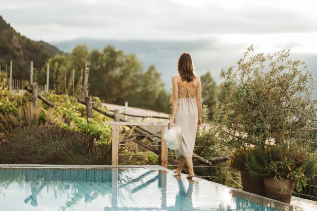 Frau am Pool mit Blick über Weinberge in Südtirol