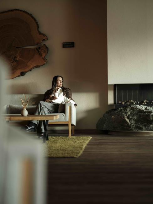 Frau sitzt auf der Couch in der Lobby und genießt ein Getränk