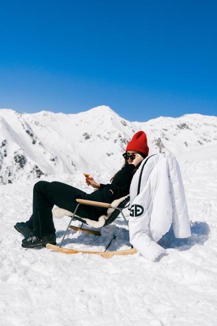 Frau mit Sekt im Liegestuhl beim Skiurlaub