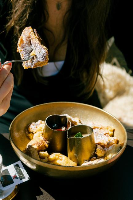 Frau isst Kaiserschmarren auf Skihütte