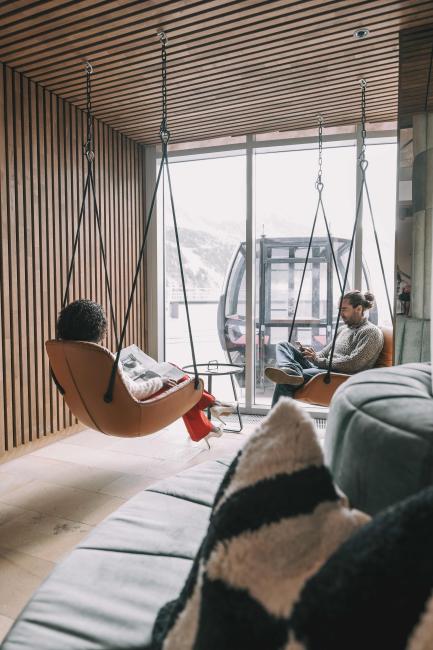 Mann und Frau sitzen in Hängeschaukeln in Lounge