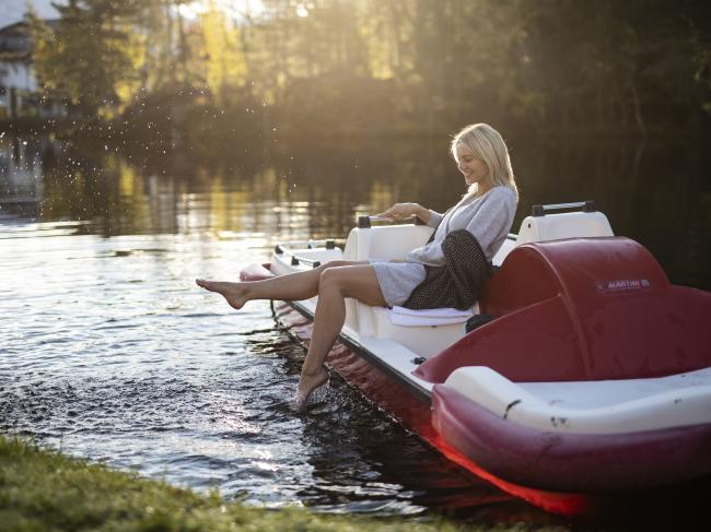 Frau sitzt am Tretboot am See vom Weihrerhof
