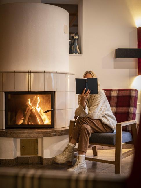 Frau liest Buch am Kamin im Weihrerhof