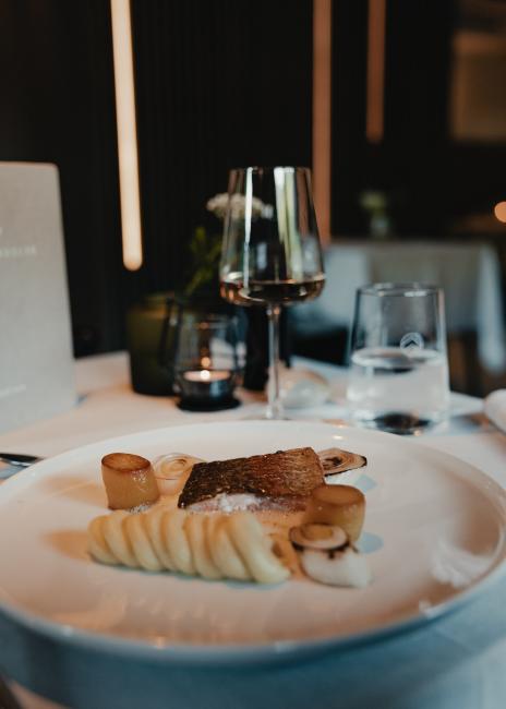 Fischgericht mit einem Glas Wein im Haus Jausern