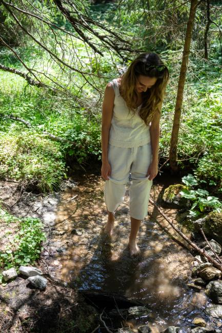 Frau spaziert durch Waldbach