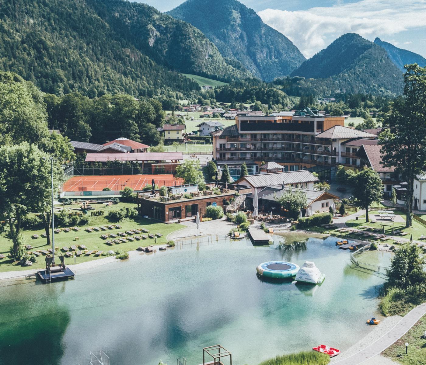 Großer Badeteich mit Hotel am Ufer und Berge im Hintergrund