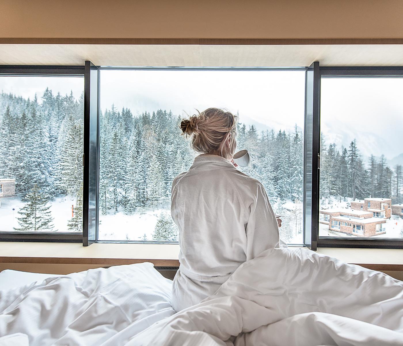 Frau sitzt mit heißem Getränk im Bett