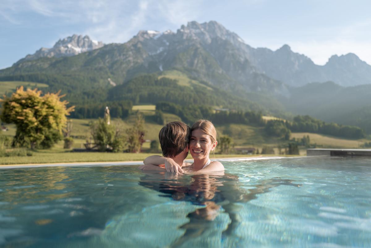 Pärchen in einem Outdoorpool mit Blick auf Berge