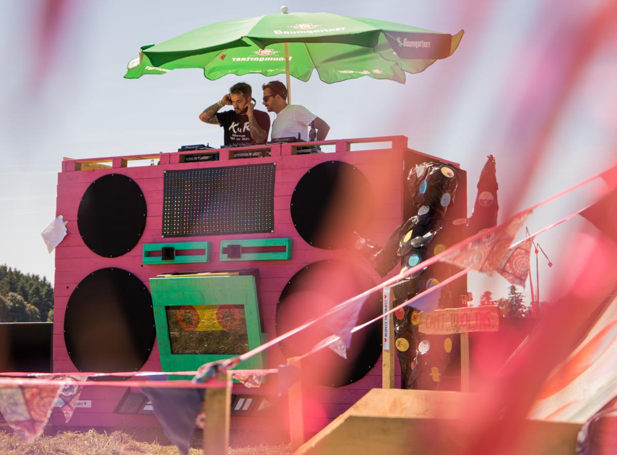 Zwei Männer an einem DJ Set unter einem grünen Sonnenschirm