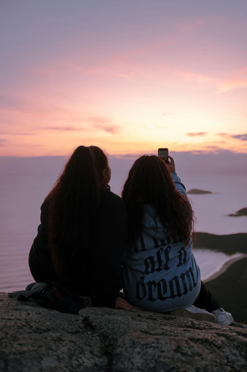 Freundinnen filmen Sonnenuntergang mit Handy