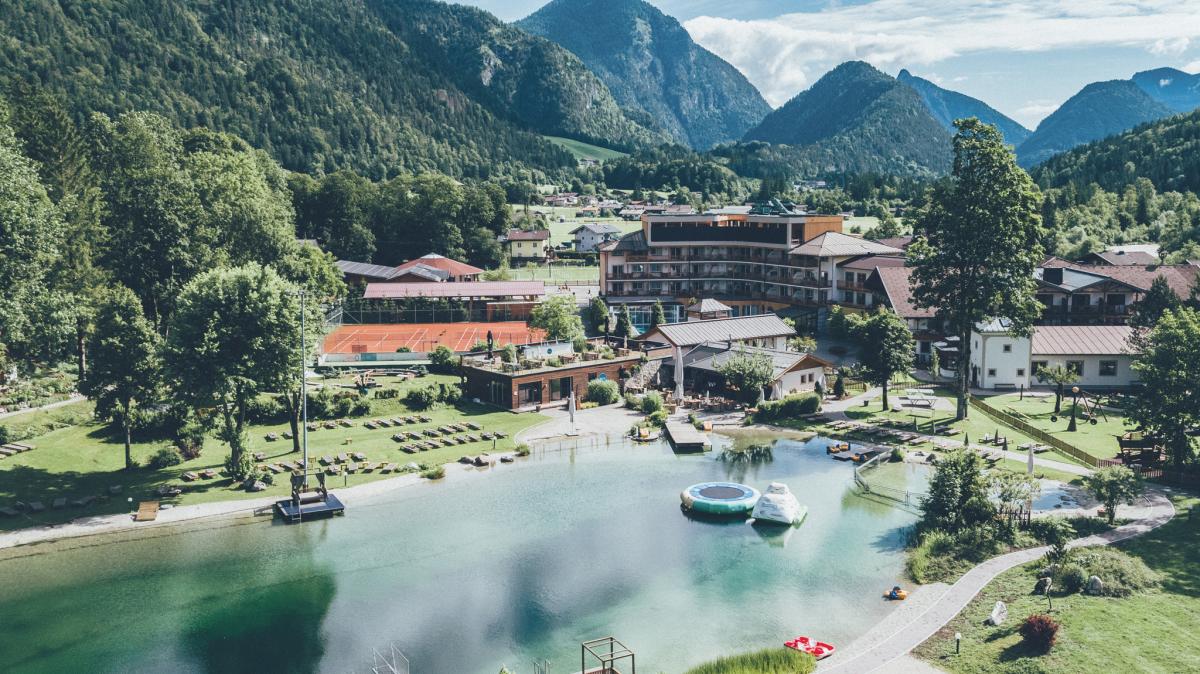 Großer Badeteich mit Hotel am Ufer und Berge im Hintergrund