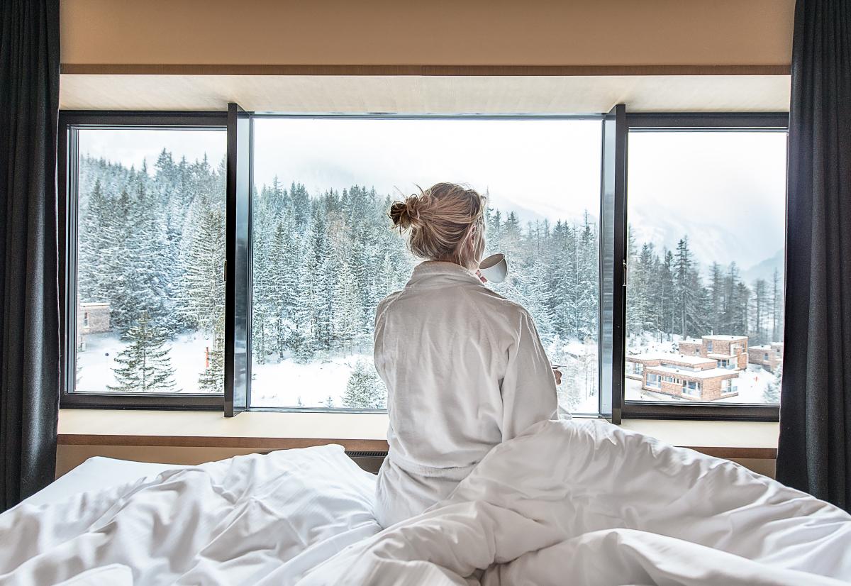 Frau sitzt mit heißem Getränk im Bett